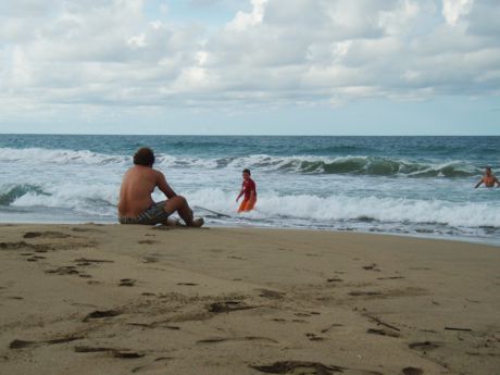 Empty Costa Rica beach with family playing in waves 